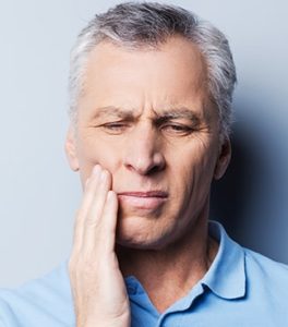 older man holding his tooth in pain