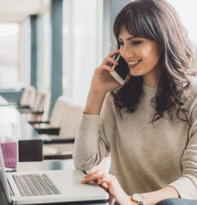 Woman in front of laptop on phone