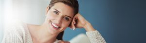 Woman smiling with dental veneers inside a dental office.