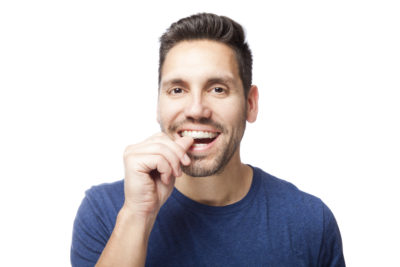 A young man with dark brown hair putting his Invisalign clear aligner onto his teeth