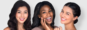 Three young, diverse women with bright white teeth posing and smiling