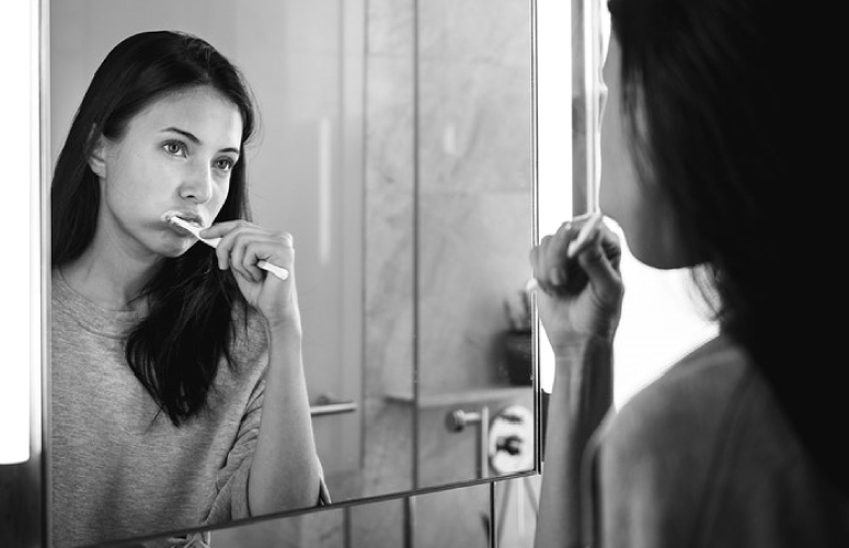 girl looking in a mirror brushing her teeth