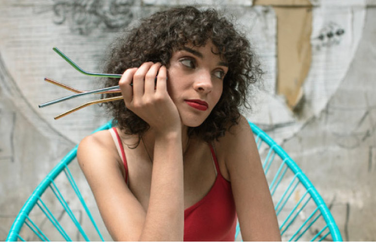 curly haired woman leaning on her hand holding straws