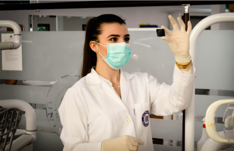 female dental hygienist wearing a mask looks at xrays