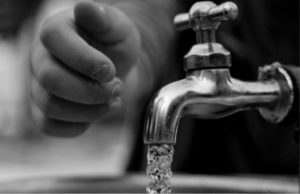 small hand reaching to turn off a running water tap