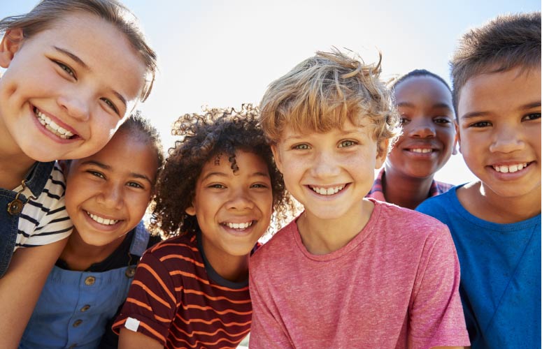 group of young kids smiling, happy to be back to school after visiting the dentist