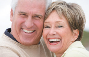 senior couple hug and smile after learning about dental veneers and crowns