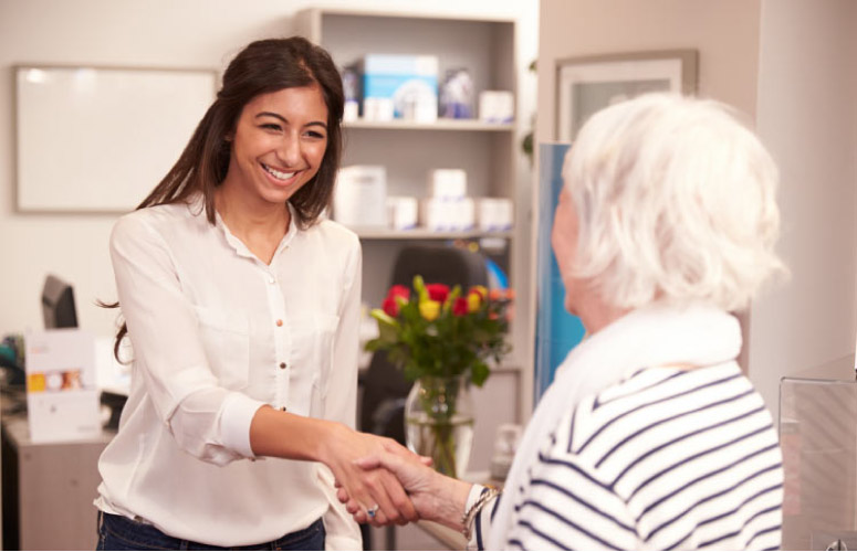elderly woman being greeted at the dentist office for a biannual checkup