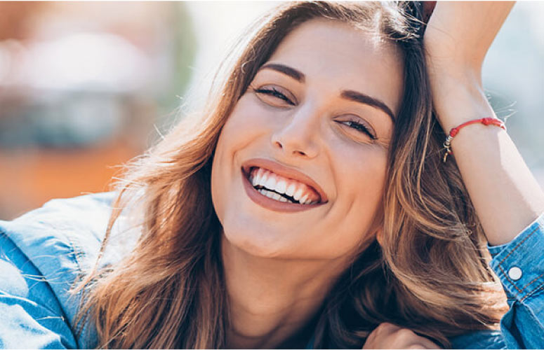 young woman smiles after getting a dental crown to restore her smile