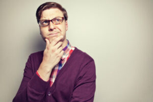 man with glasses holds his chin and ponders how long dental crowns last