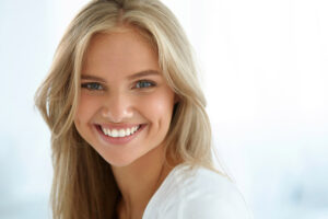 young blond woman smiles to show off her bright, white, straight teeth.
