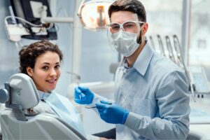 young woman in the dentist chair getting a checkup from a masked dentist