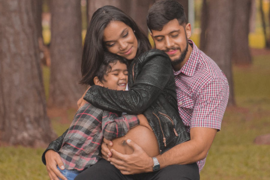 pregnant woman hugging with her son and husband
