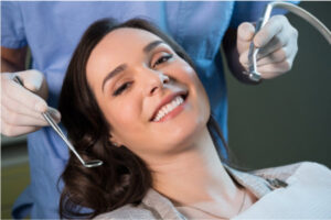 young woman sitting in the dentist chair smiles while receiving cosmetic treatments