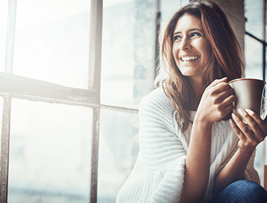 woman drinking coffee and looking out the window