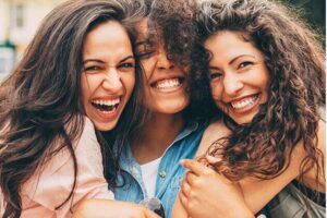 three young women smile showing off their perfect teeth