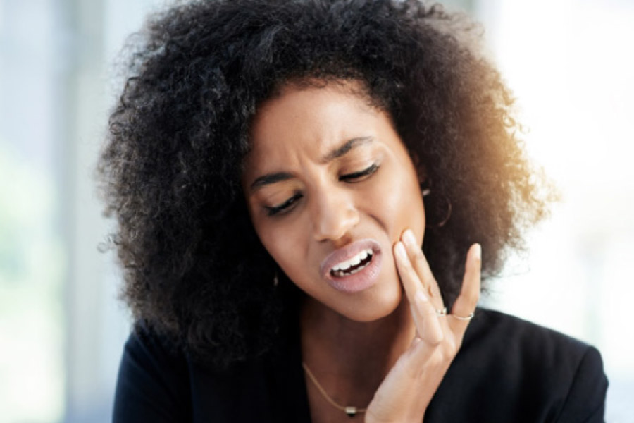 young woman holds her jaw in pain with a dental emergency