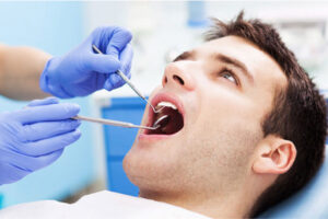 young man gets an oral cancer screening at the dentist