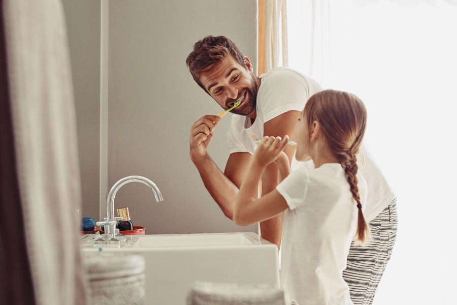 dad brushes his teeth alongside his young daughter