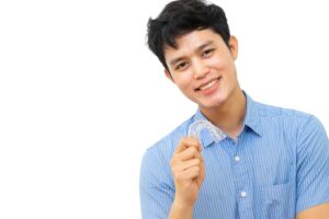 young man holds his Invisalign clear aligner