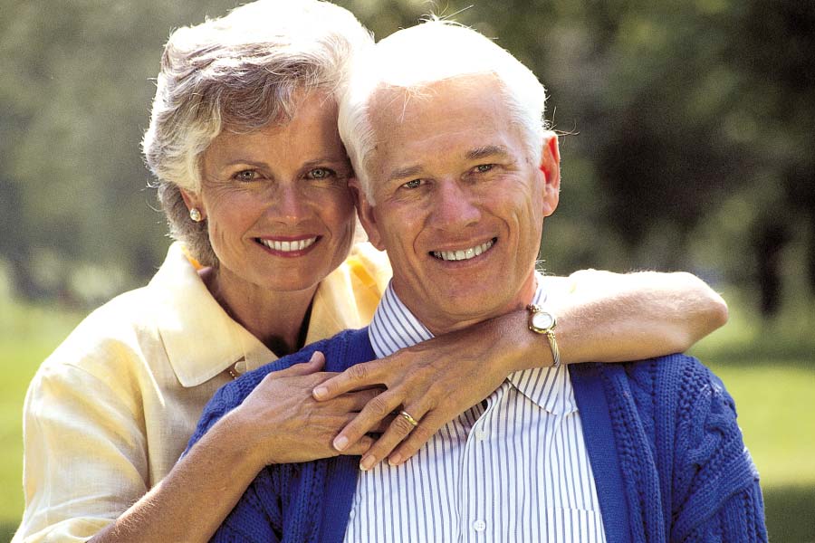 senior couple smile and hug after learning about dental crowns, bridges and veneers