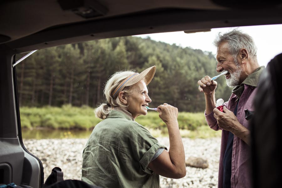 senior couple brush their teeth together while camping