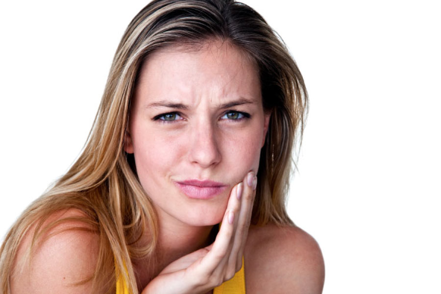 woman holds her jaw in pain from a toothache