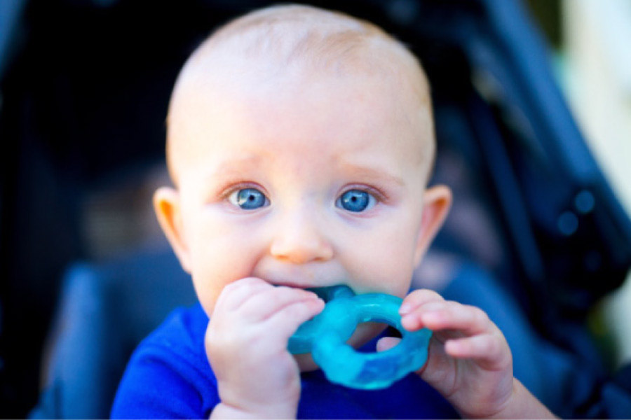 blue eyed baby boy teething on a blue teething ring