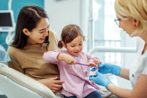 child in dental chair with parent getting oral hygiene tips for kids