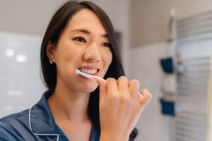 woman brushing her teeth to prevent early gum disease